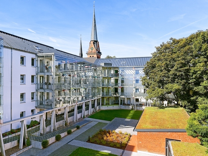 Ein Mehrparteienhaus nach der Renovierung von außen mit weißer Fassade und neuen Balkonen Ein Mehrparteienhaus nach der Renovierung von außen mit weißer Fassade und neuen Balkonen
